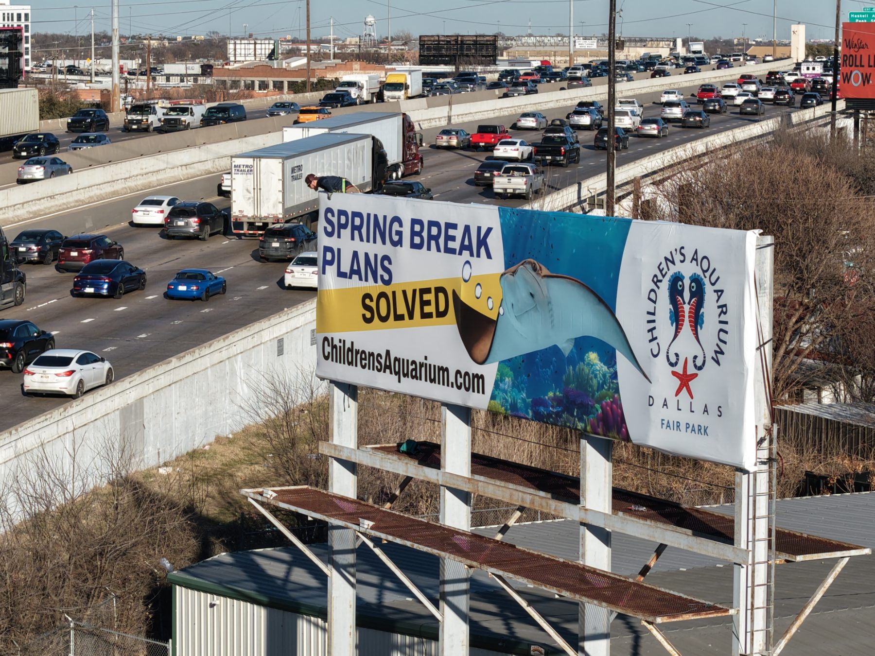 Children’s Aquarium Dallas 'Spring Break Plans Solved' billboard over I-30 traffic